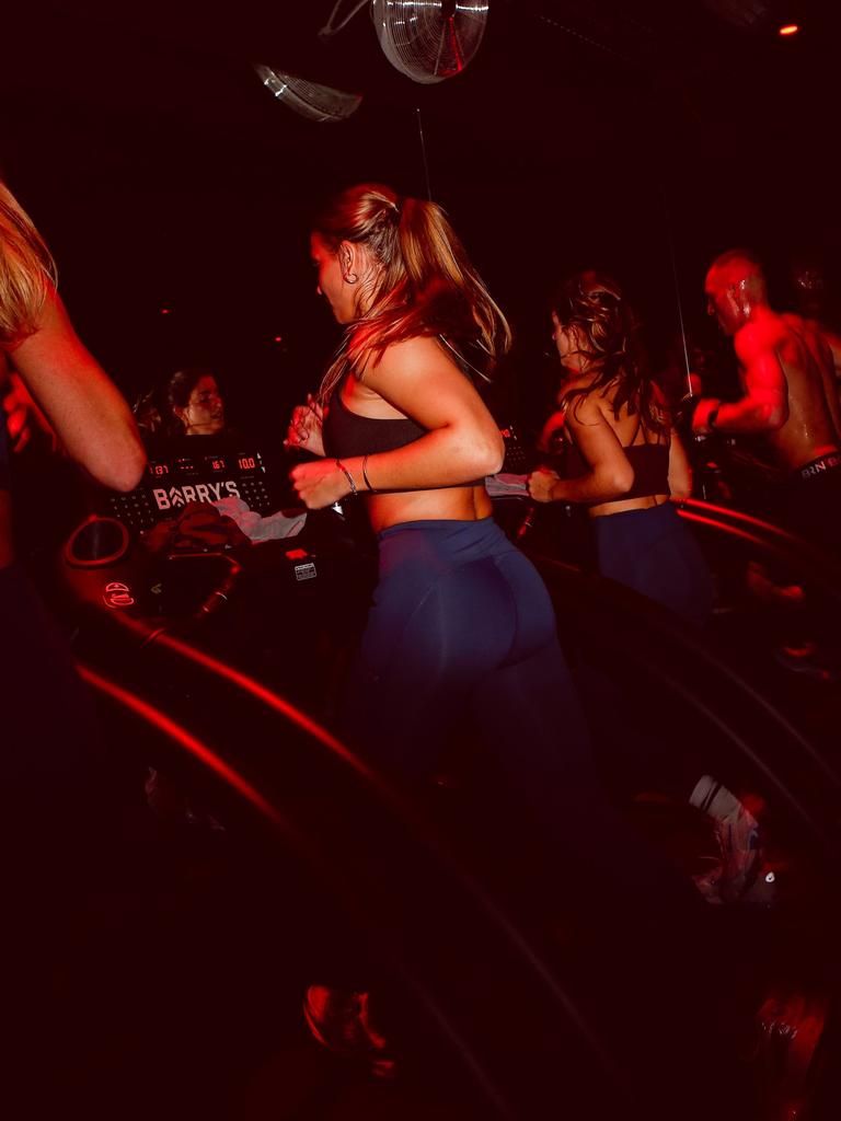 Woman running on a treadmill in Barry’s studio, wearing a black sports bra and navy Björn Borg tights.