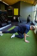 A blond woman doing mountain climbers at the gym. She is wearing a blue sports bra and matching Sleek Tights from Björn Borg